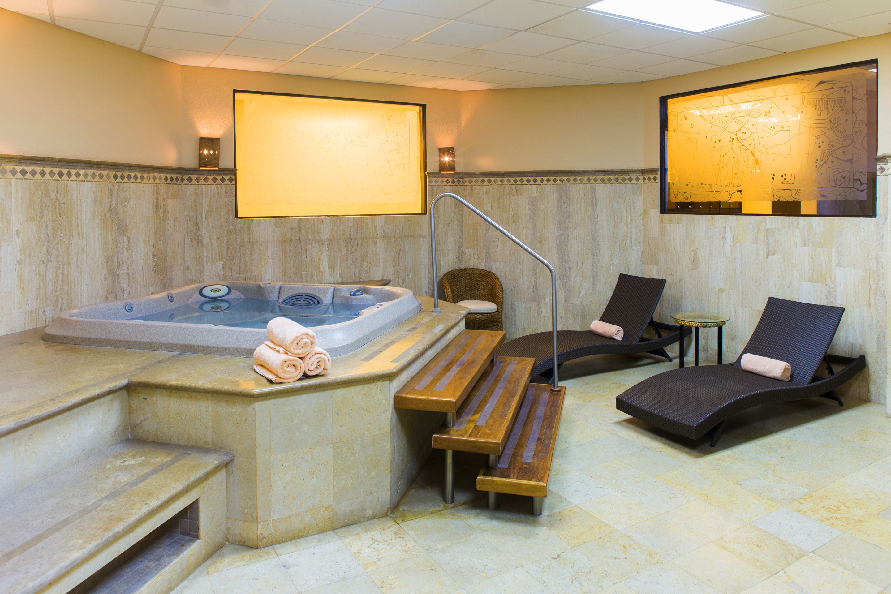 A spa area with a hot tub, wooden benches, and lounge chairs.