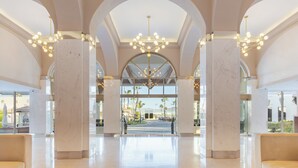 Eine geräumige Lobby mit hohen Decken, großen Marmorsäulen und einem zentralen Kronleuchter.