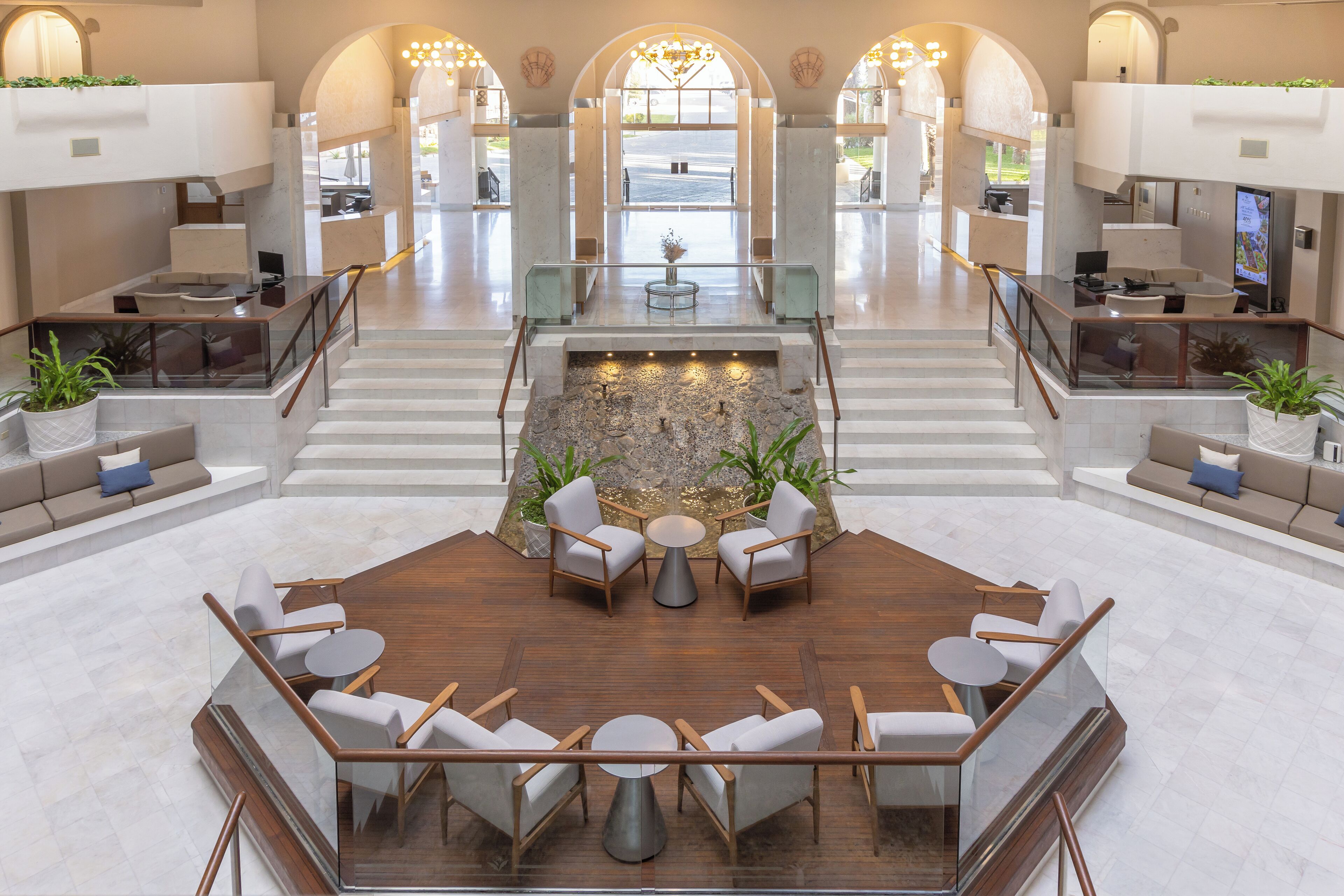 A spacious lobby with a central seating area, a fountain, and a view of the outdoors.