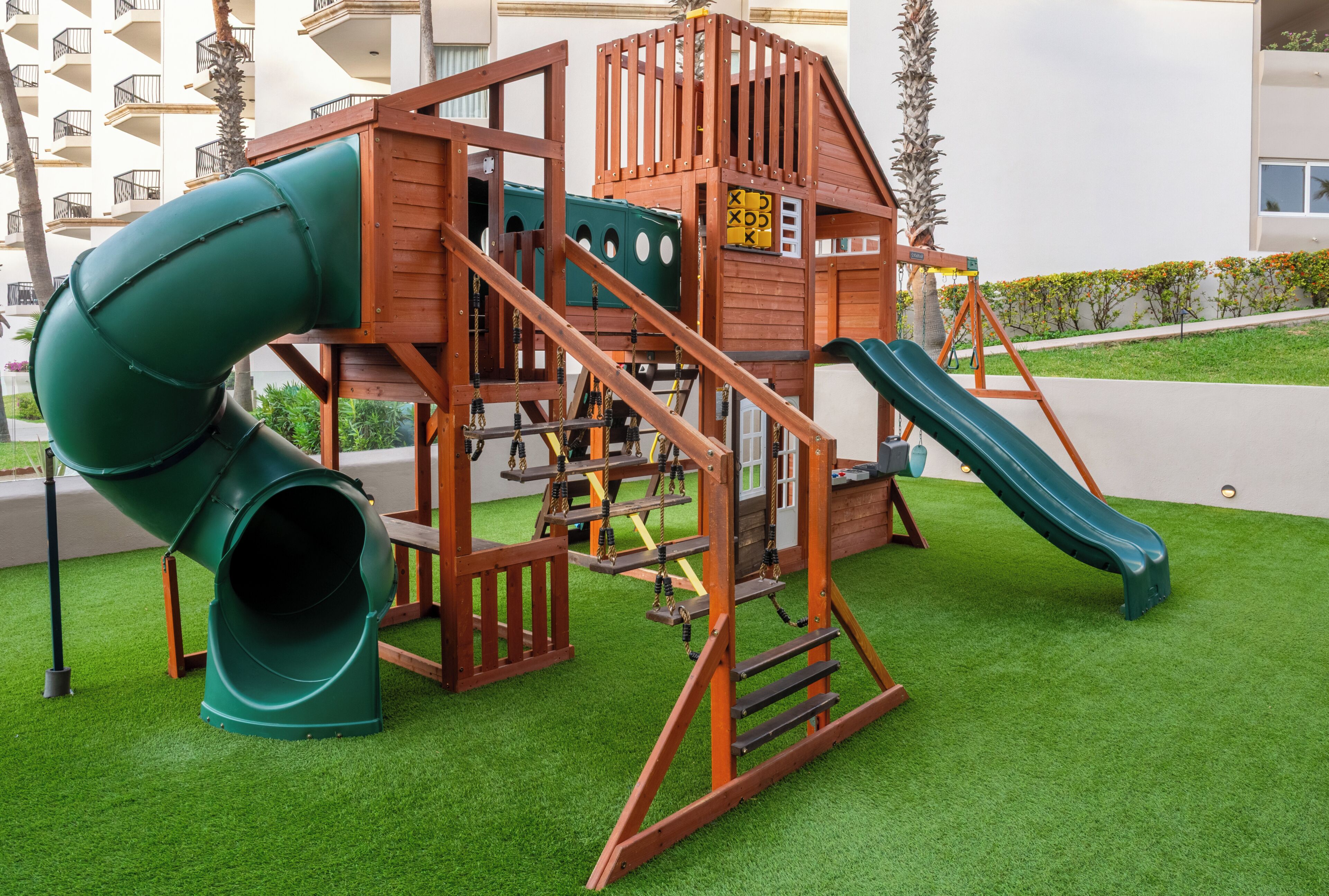 Un'area giochi con uno scivolo, una struttura per arrampicarsi e un tunnel verde.