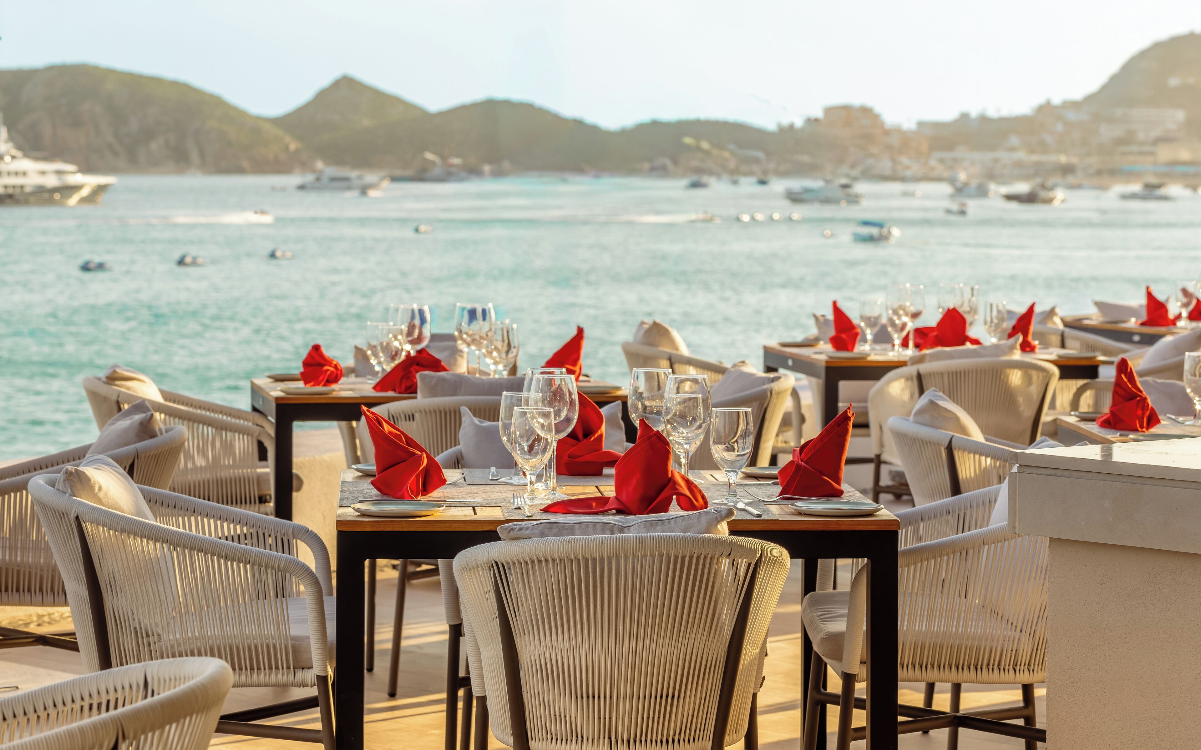 A seaside restaurant with tables set for dining, overlooking the sea.