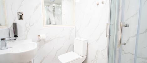 A bathroom with a toilet, sink, and shower.