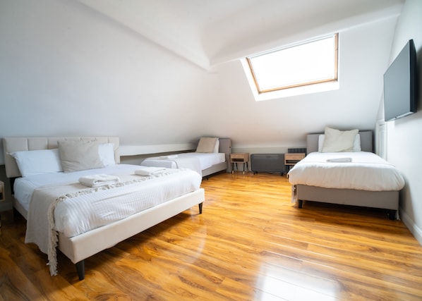 A bedroom with two beds, a skylight, and a wooden floor. - Rushmore Hotel (London)