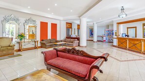 A spacious lobby with a reception desk, sofas, and a large mirror. - BreakFree Moroccan (Surfers Paradise)