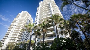 A high-rise hotel with multiple balconies and palm trees in the foreground. - BreakFree Moroccan (Surfers Paradise)