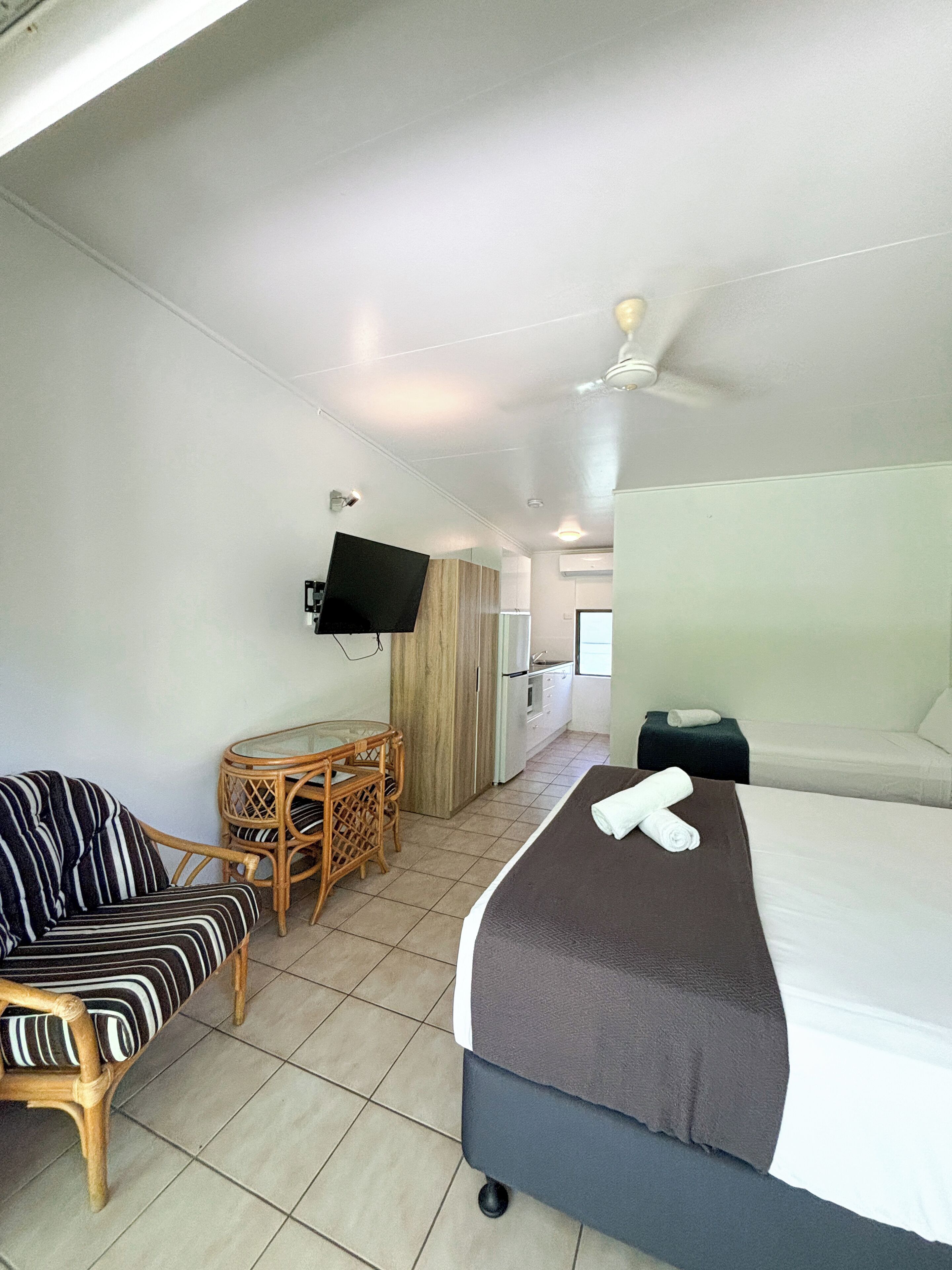 Ein Hotelzimmer mit Bett, Wandfernseher, Esstisch mit Stühlen und einer Couch.
