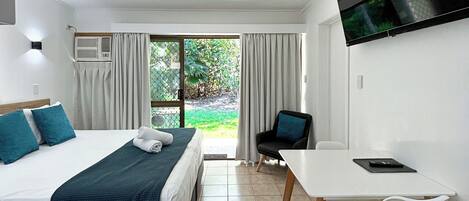 A hotel room with a bed, a desk, a chair, a TV, and a ceiling fan.