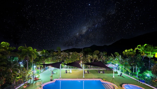 A nighttime view of a pool area with a clear sky, stars, and a mountain in the background. - Amaroo Rainforest Resort (Nelly Bay)