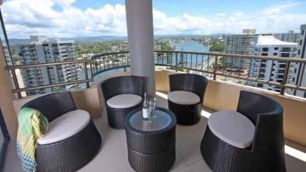 A balcony with wicker furniture and a view of a cityscape and water.