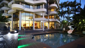 A modern hotel with a pool area, featuring a curved balcony and large windows.