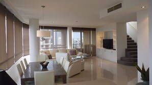 A modern living room with a sofa set, a dining table, and a TV.