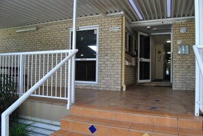 A reception area with a tiled floor, a white staircase, and a brick wall.