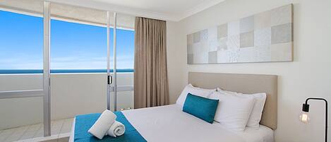 A hotel room with a large bed, a view of the sea, and a modern design.