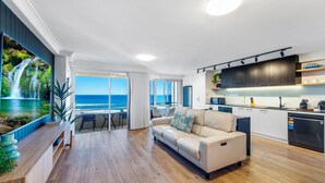 Una sala de estar moderna con un televisor grande, un sofá y vistas al océano.