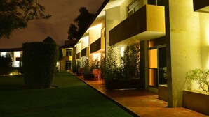 A modern hotel with multiple balconies, outdoor seating, and well-lit pathways. - Hotel Las Trojes (Aguascalientes)