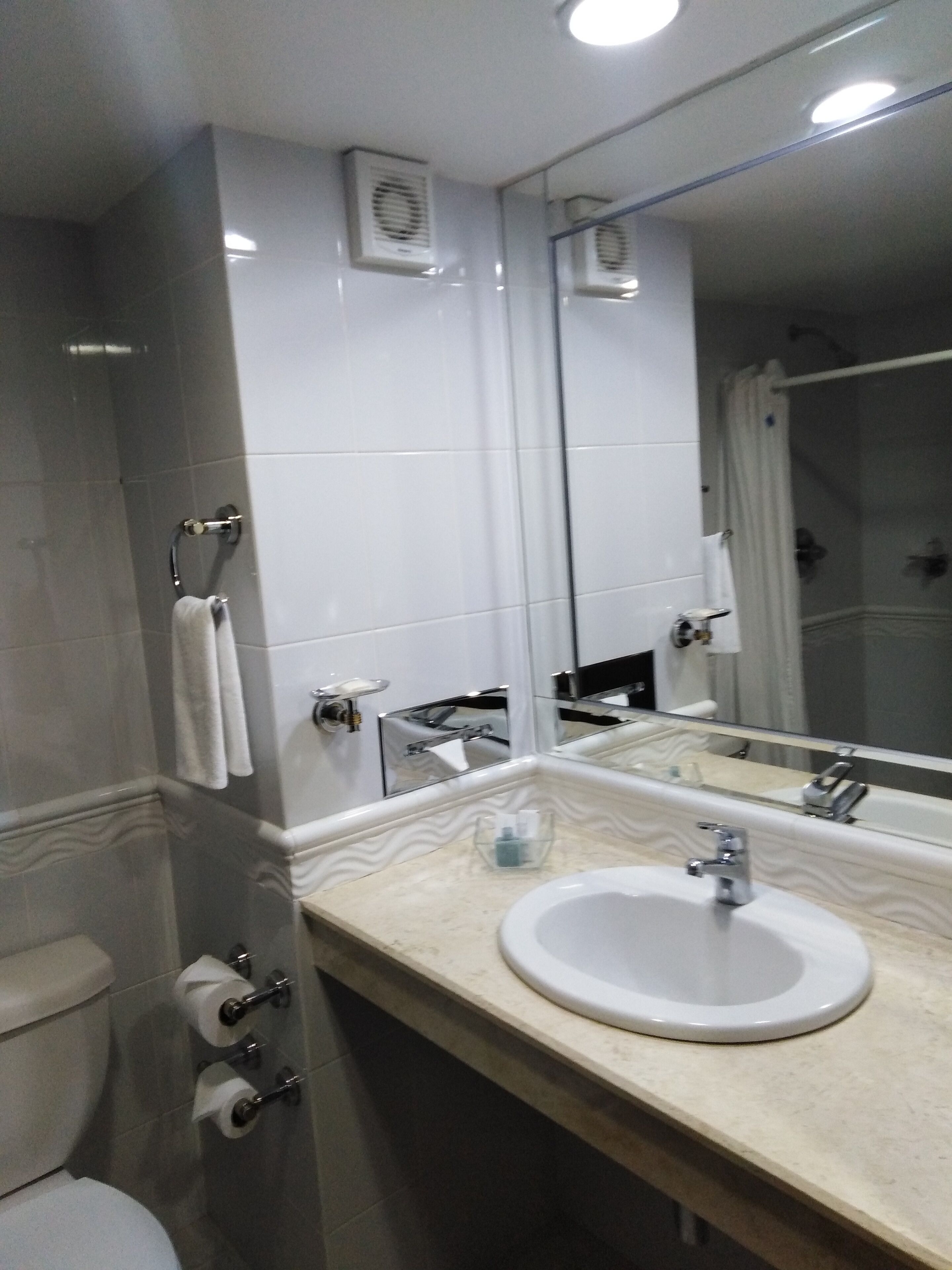 Un baño moderno con lavamanos, espejo y retrete blancos.