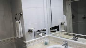 Un baño moderno con lavamanos, espejo y retrete blancos.