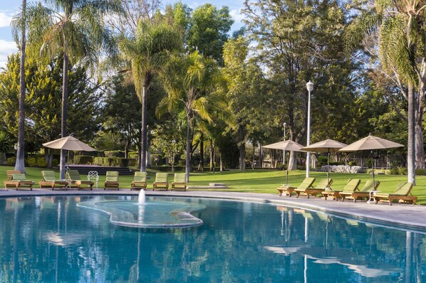 Una piscina al aire libre, sombrillas, tumbonas