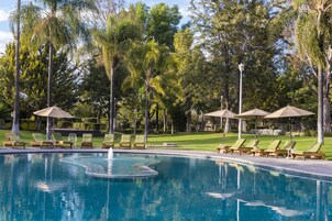 Una piscina al aire libre, sombrillas, sillones reclinables de piscina