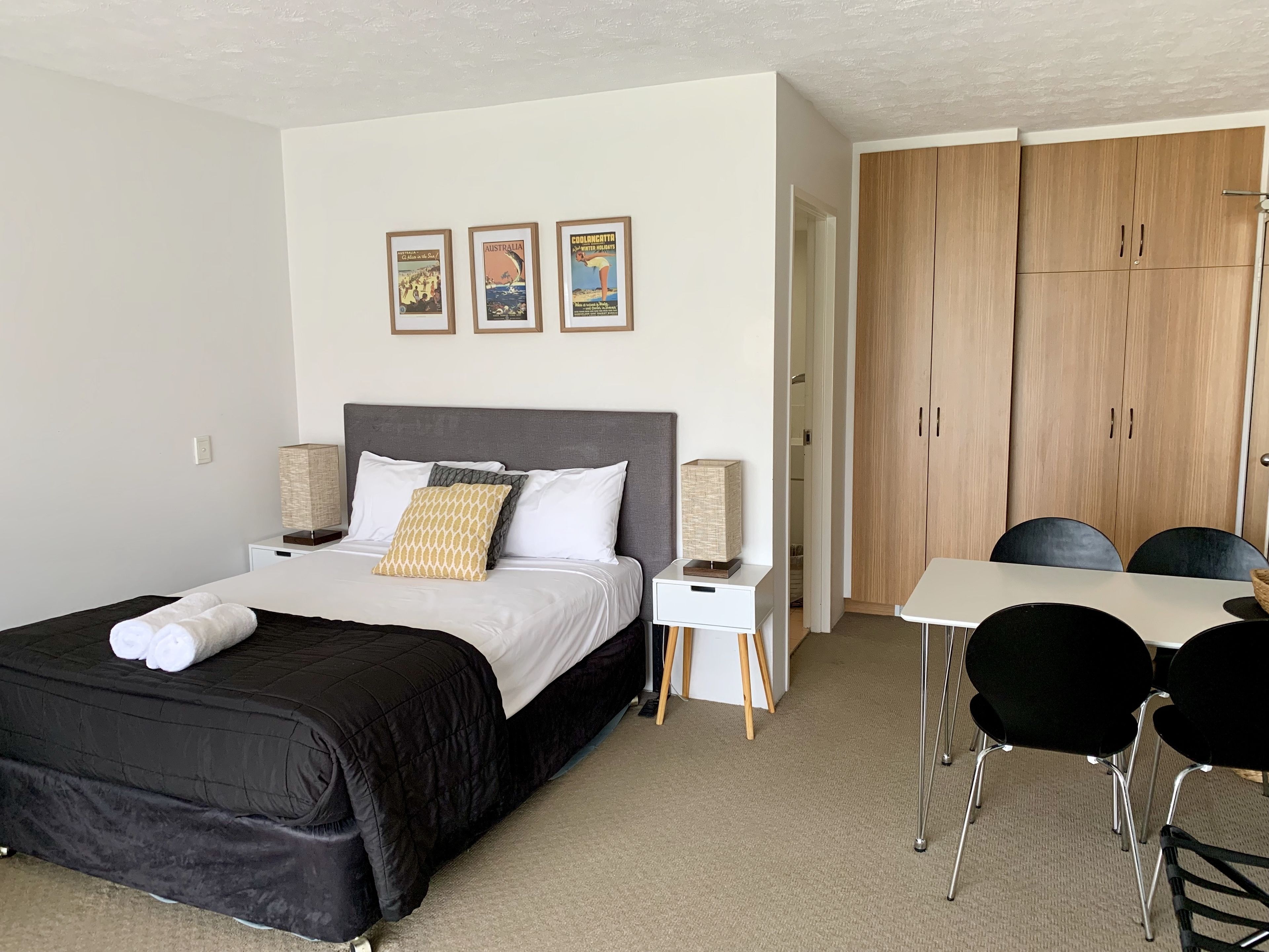 A hotel room with a bed, bedside tables, a desk with chairs, and a wardrobe.