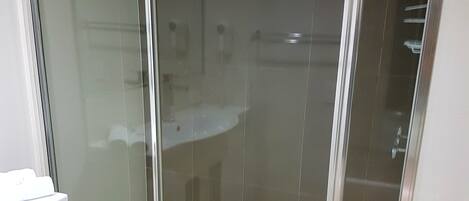 A modern bathroom with a glass-enclosed shower, a white sink, and a toilet.