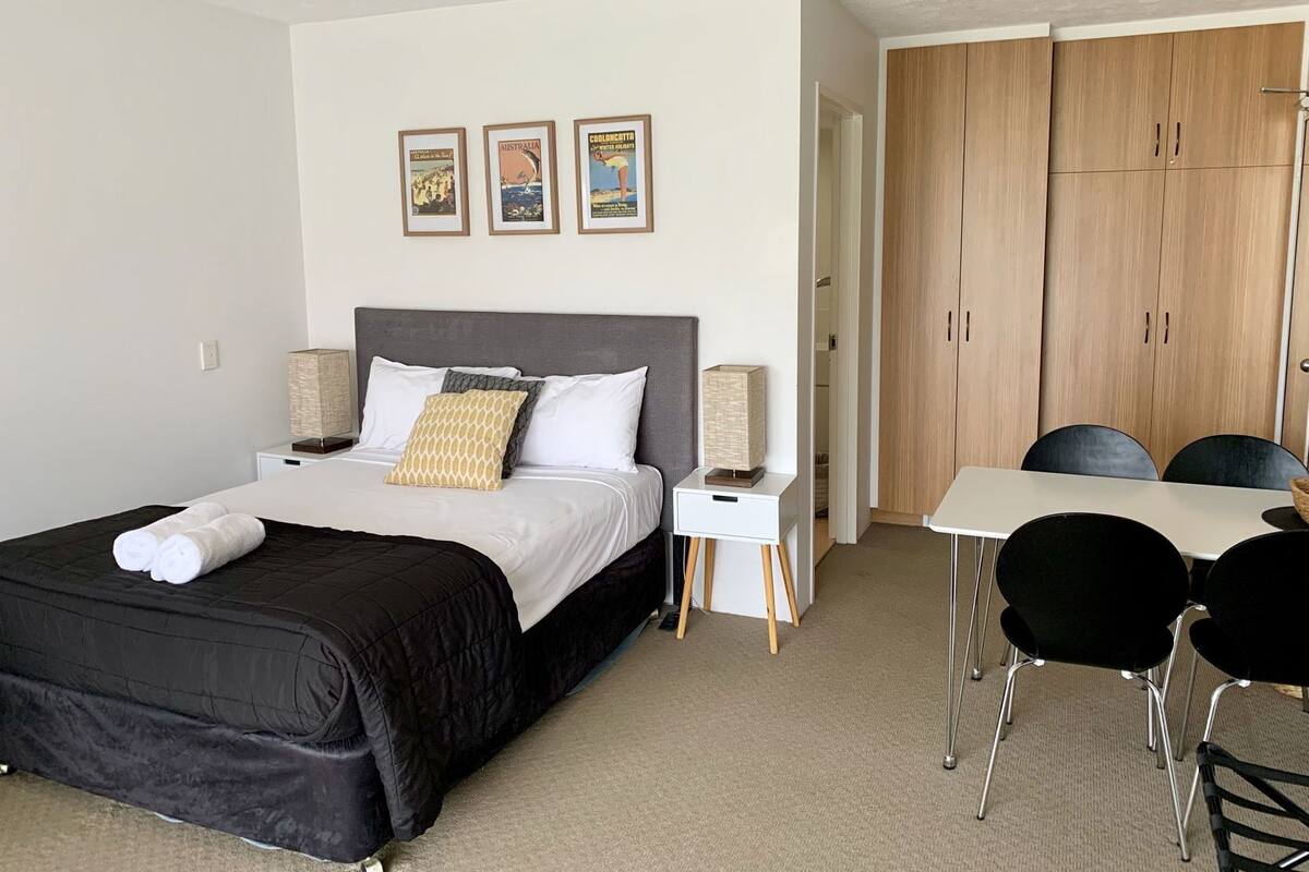 A bedroom with a bed, bedside tables, a desk, chairs, and a wardrobe.