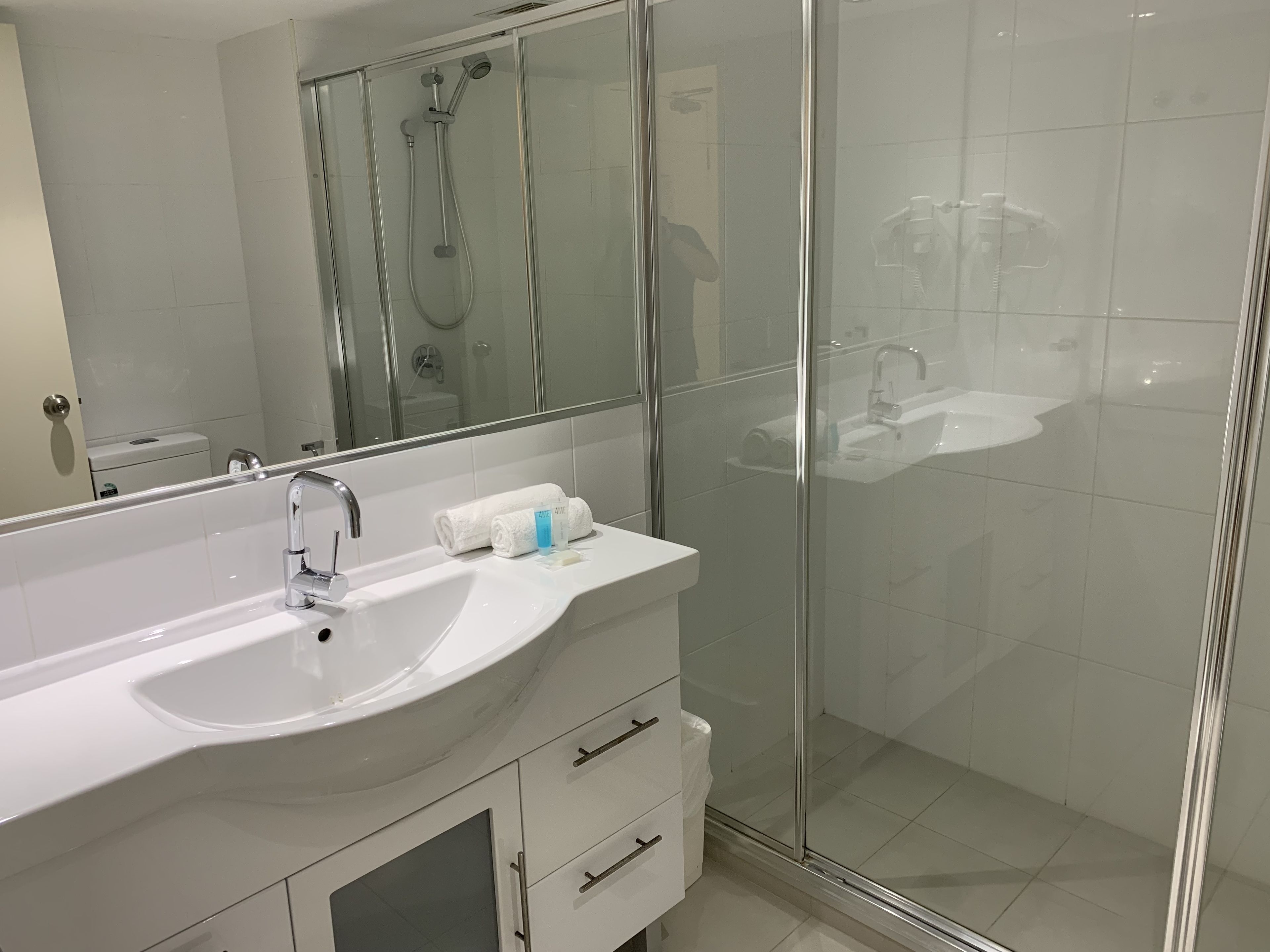 A modern bathroom with a glass-enclosed shower, a white sink, and a mirror above it.
