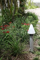 Un jardín con flores rojas y un objeto cónico blanco.