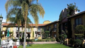 Un patio con palmeras, mobiliario exterior y una estatua.