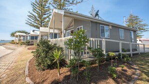 A mobile home with a covered porch, satellite dish, and a view of the beach. - Broadwater Tourist Park (Southport)