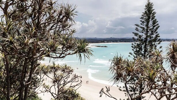 A beach with clear turquoise water, surrounded by dense tropical vegetation. - Greenmount Beach House (Coolangatta)