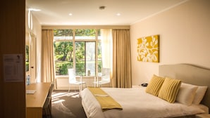 A hotel room with a large bed, a desk, and a window with curtains. - Foreshore Motor Inn (Whyalla)