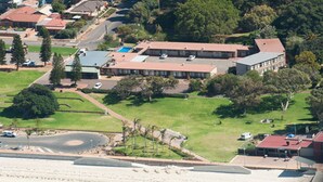 An aerial view of a coastal residential area with houses, a beach, and a large building with a red roof. - Foreshore Motor Inn (Whyalla)
