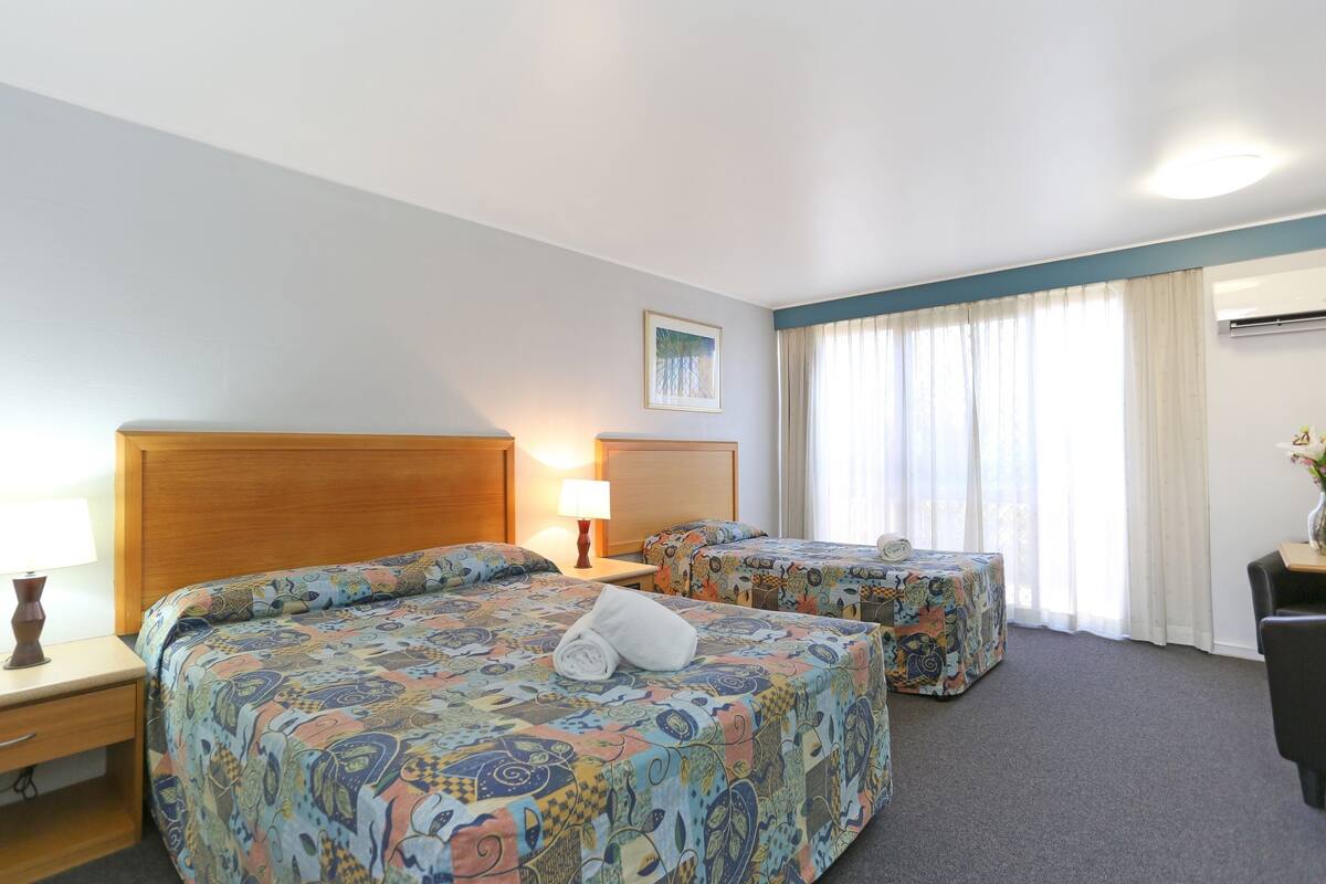 Een hotelkamer met twee bedden, een nachtkastje, een lamp, een bureau en een stoel.