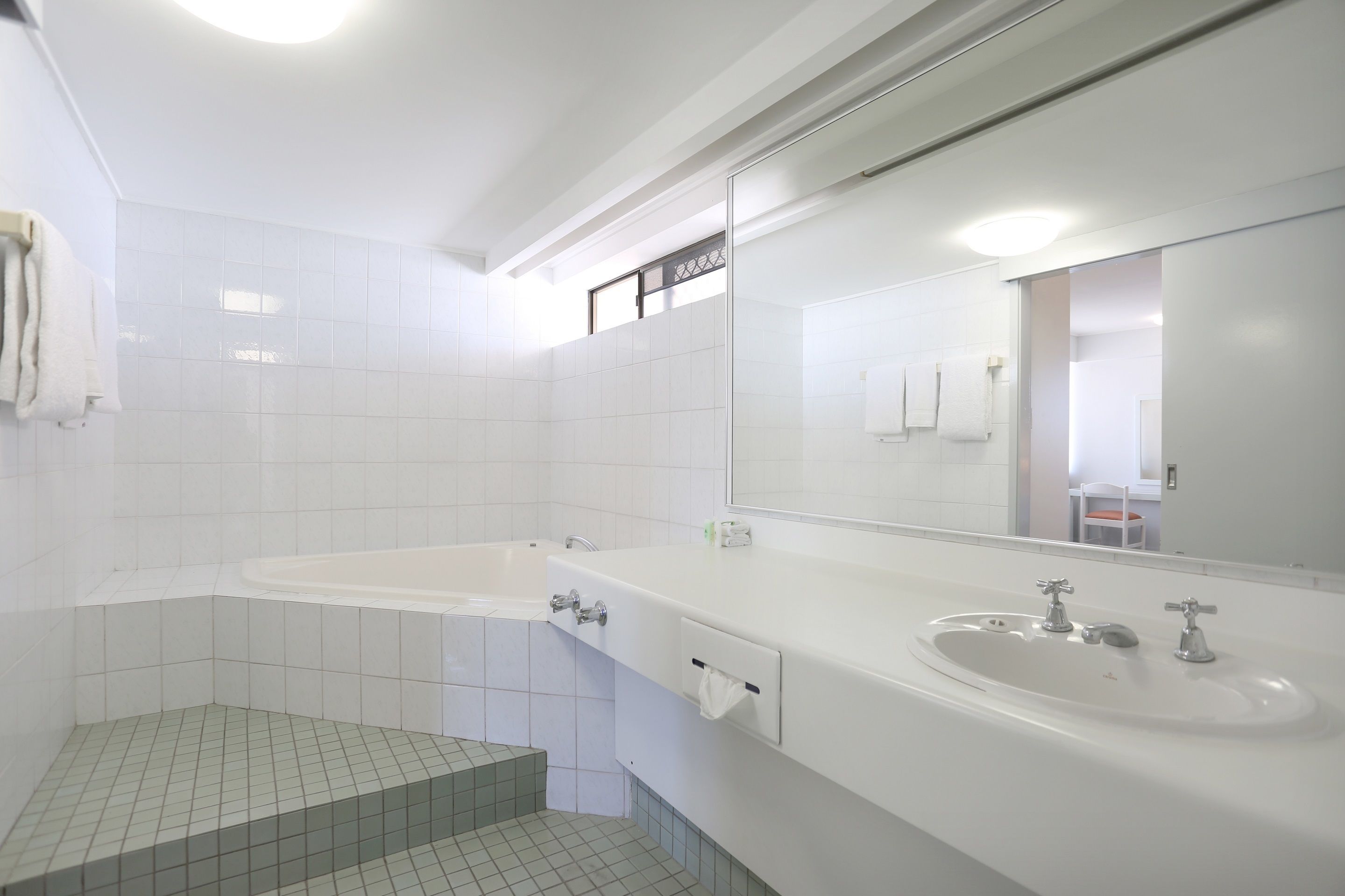 A modern bathroom with a large bathtub, a sink, and a mirror.