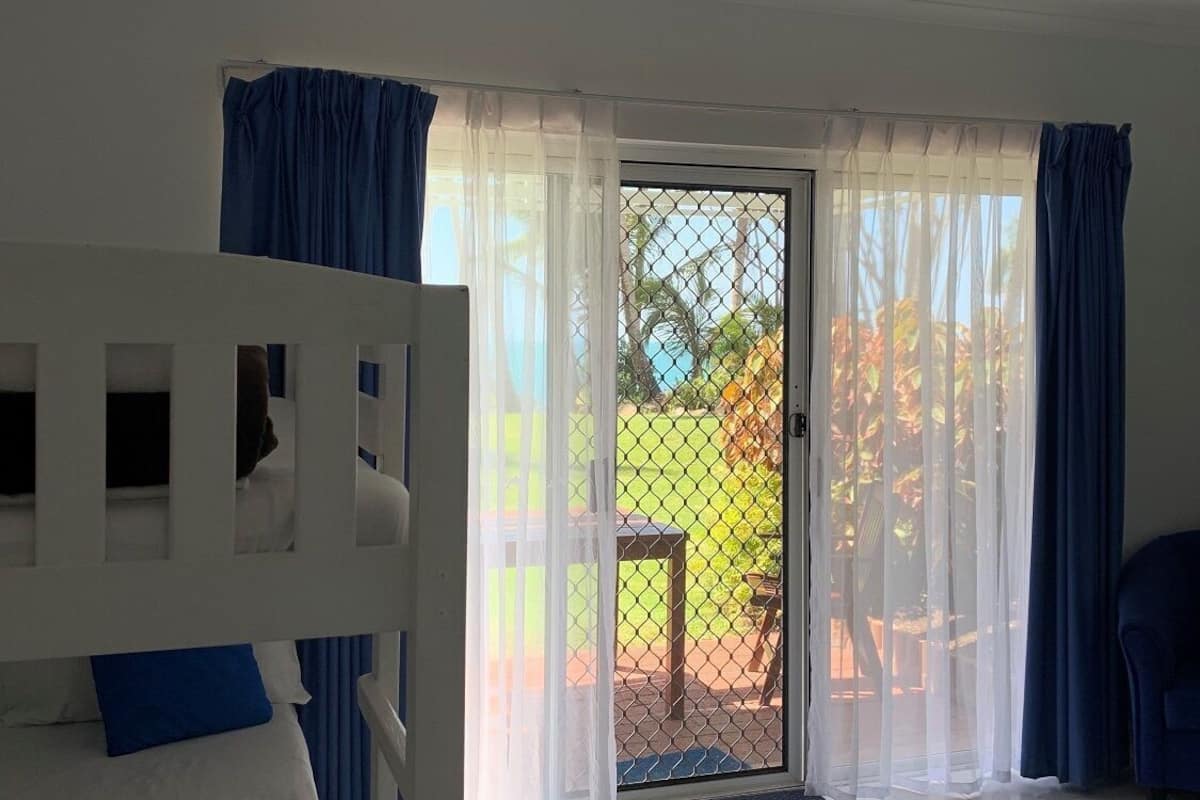 Una habitación con literas, una puerta corrediza de vidrio y vistas a un jardín.
