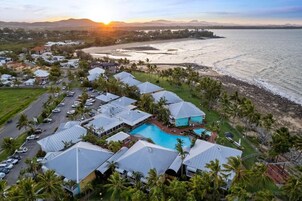 Un resort costero con varias edificaciones tipo bungalow, una piscina y una playa.