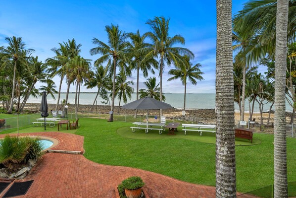 A well-maintained outdoor area with a pool, picnic tables, and a view of the beach.