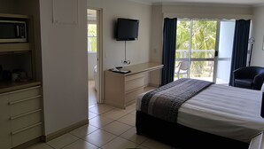 Une chambre d’hôtel équipée d’un lit, d’un bureau, d’une télévision, d’une chaise et offrant une vue sur l’extérieur.