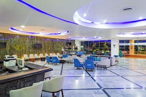 A hotel lobby with a reception desk, seating area, and a bar. - Sunset Royal Beach Resort (Cancun)