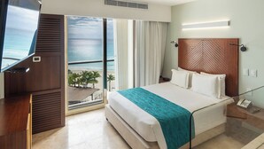 Habitación de hotel con cama, televisor, vista al océano y cabecera de madera.