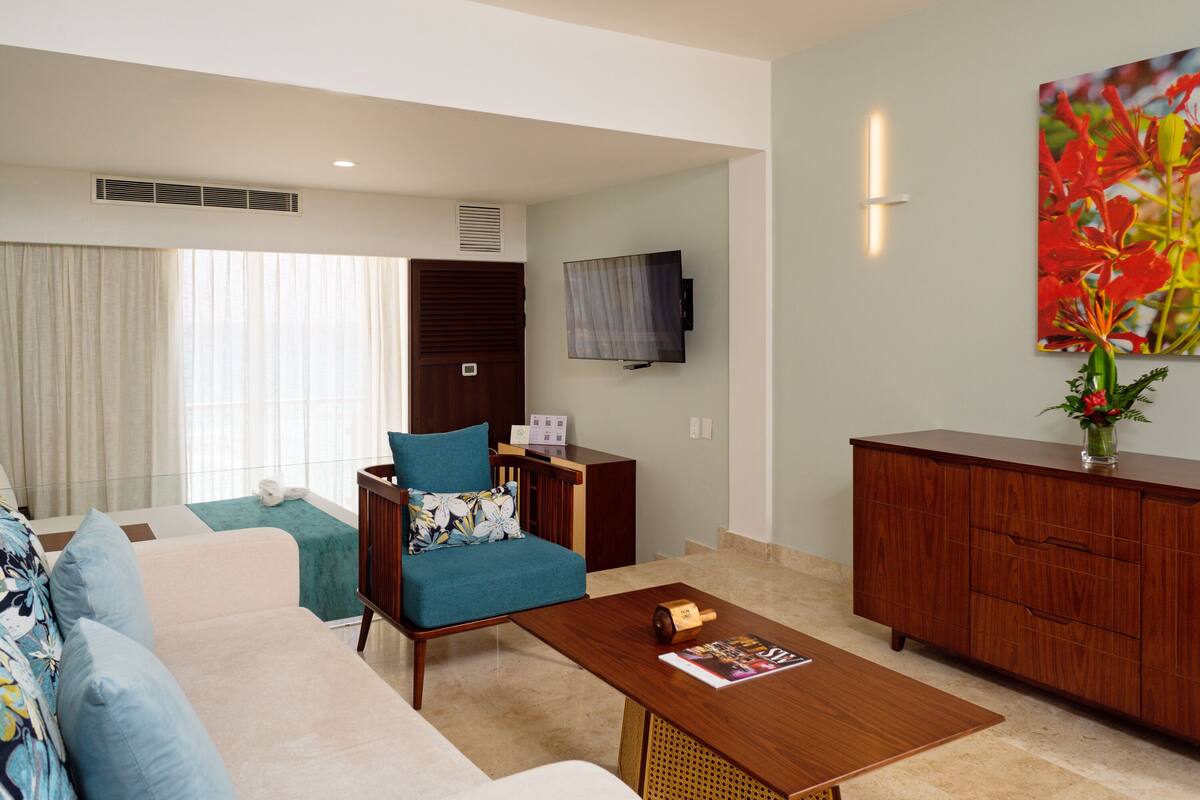 A modern living room with a sofa, armchair, coffee table, TV, and a cabinet.