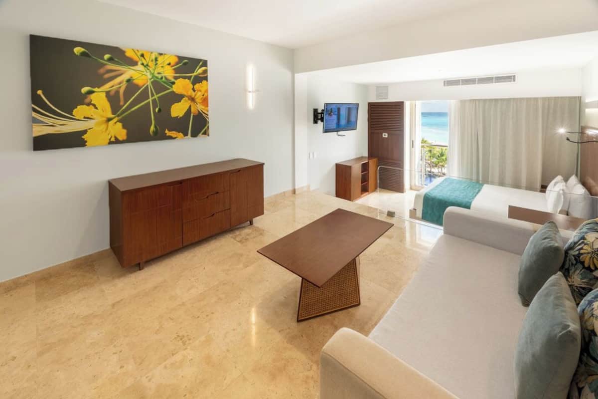 A modern living room with a sofa, a coffee table, a TV, and a painting of yellow flowers.
