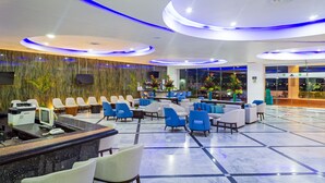 Un vestíbulo de hotel con una recepción, zona de estar y un ventanal grande.