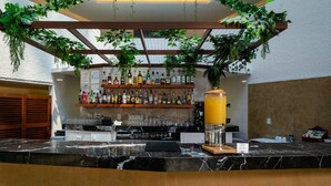 Zona de bar con encimera de mármol, estanterías llenas de botellas de licores y plantas colgantes.
