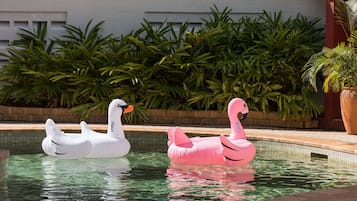 Una piscina al aire libre, sillones reclinables de piscina