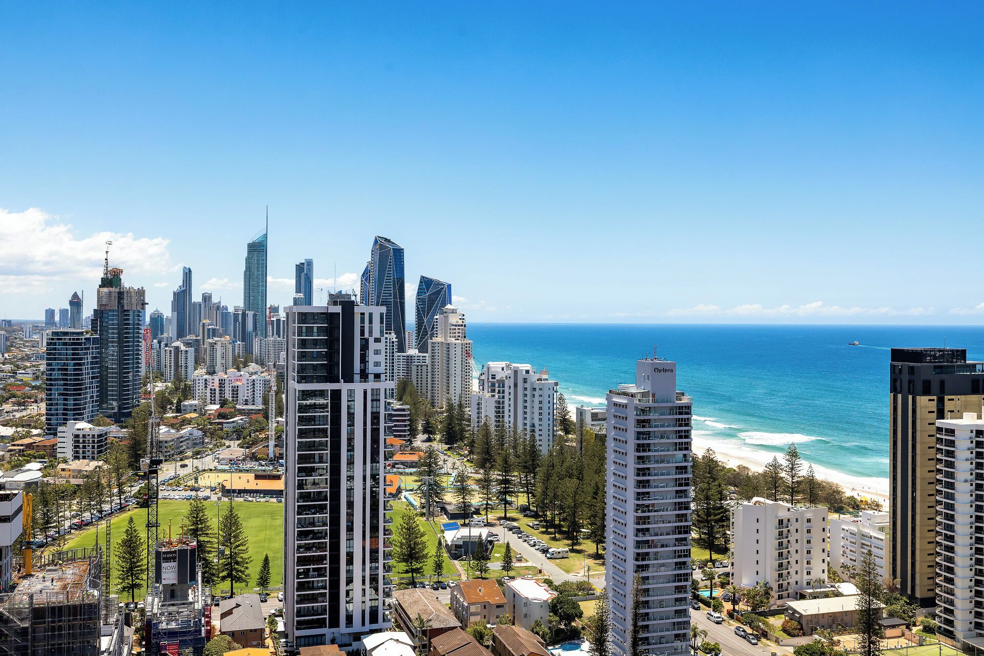A coastal cityscape with high-rise buildings, a clear blue sky, and a beach in the distance.