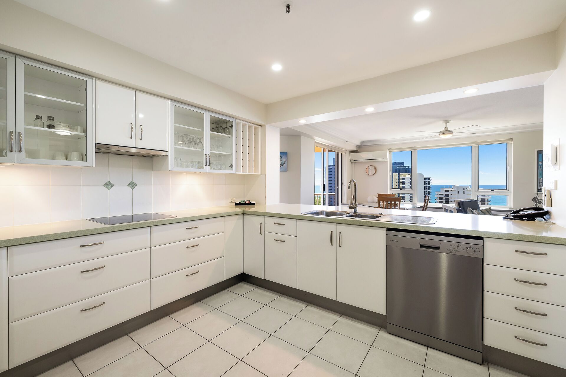 Una cocina moderna con armarios blancos, lavavajillas y vistas a la ciudad.