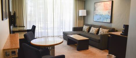 Una habitación de hotel con sofá, una mesa redonda y televisión.