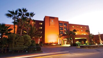 Un hotel con un letrero llamativo, varios pisos y una entrada bien iluminada.